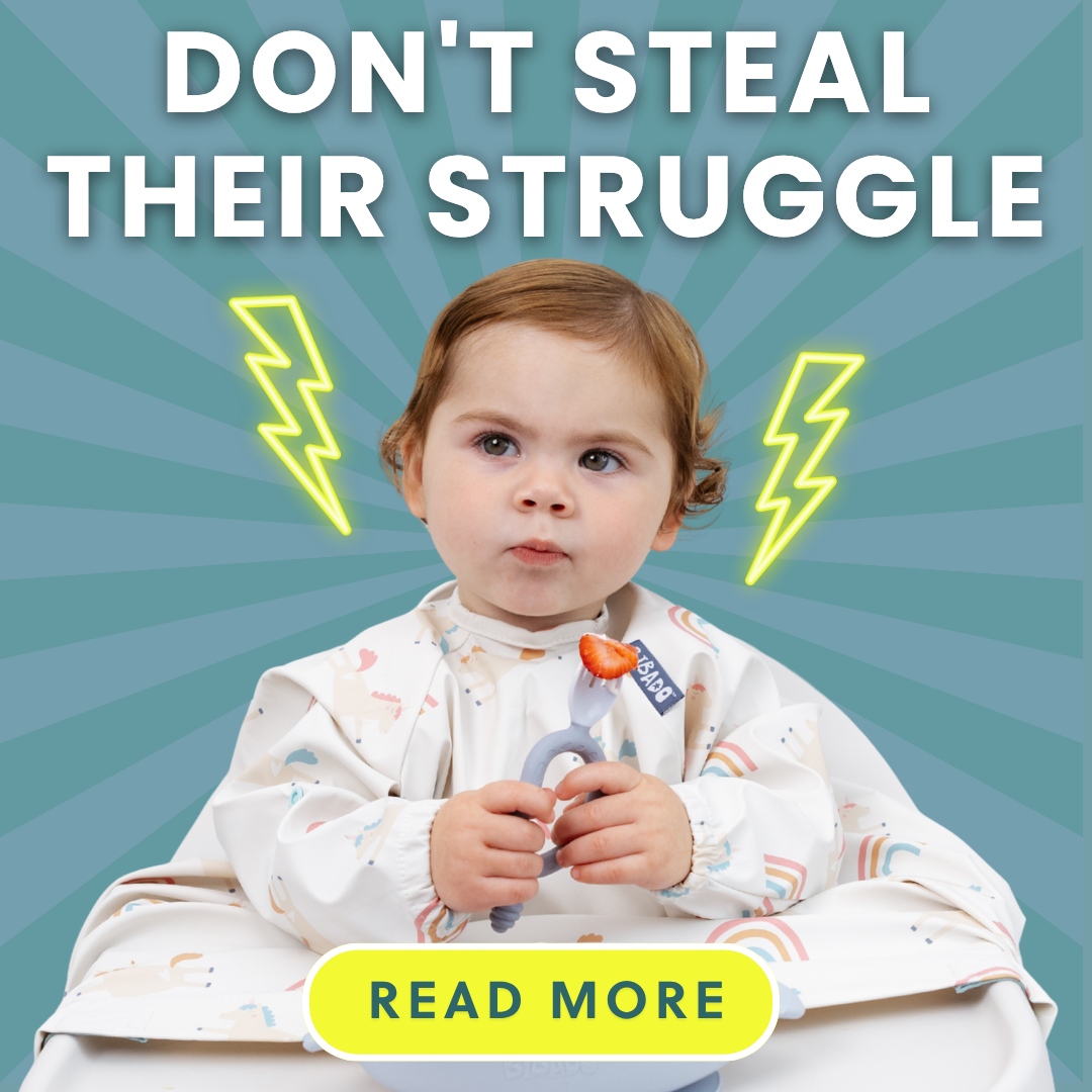 Toddler in a rainbow bib, holding a teether with a strawberry, looking thoughtful.