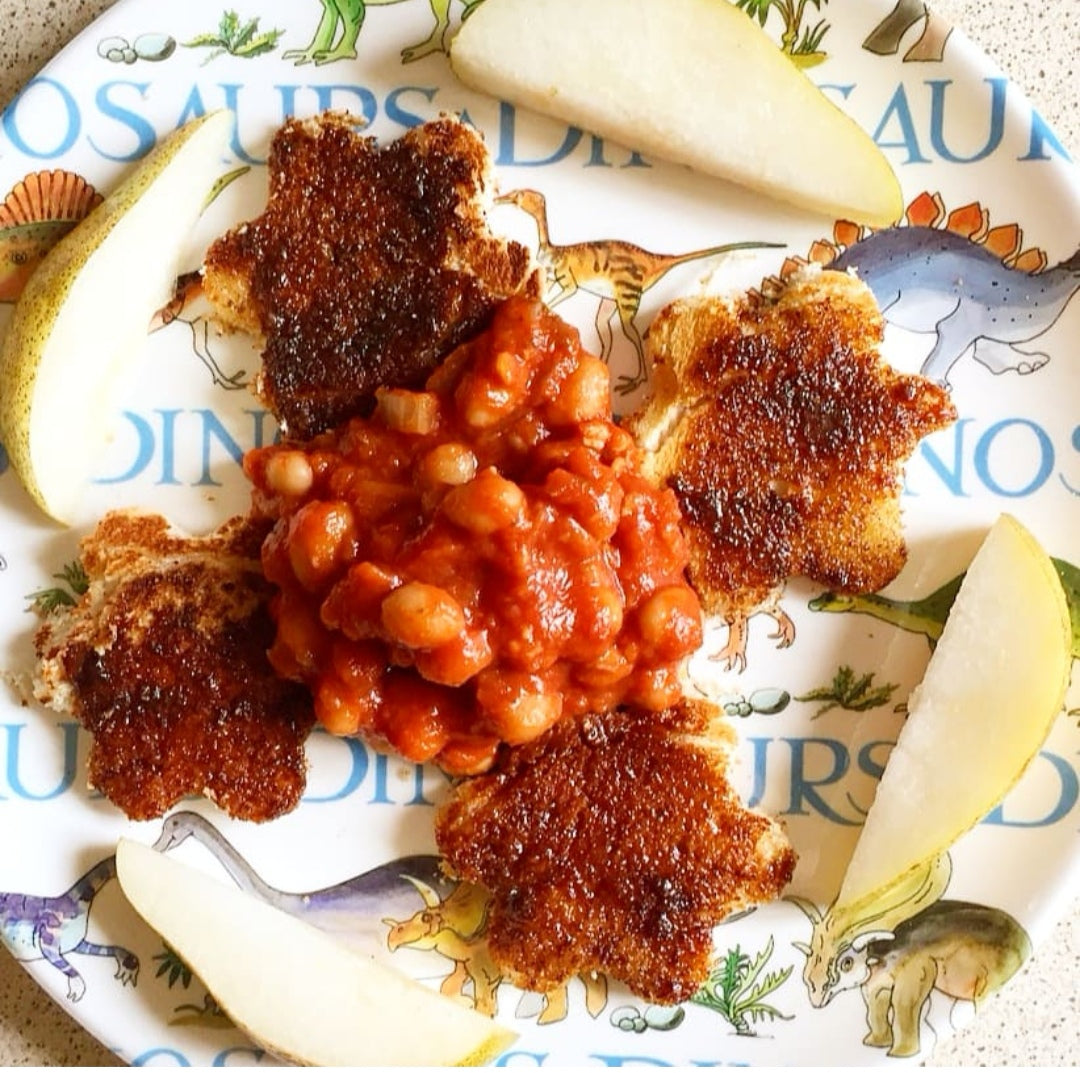 Baked beans with hidden veggies on dinosaur toast, served with pear slices.