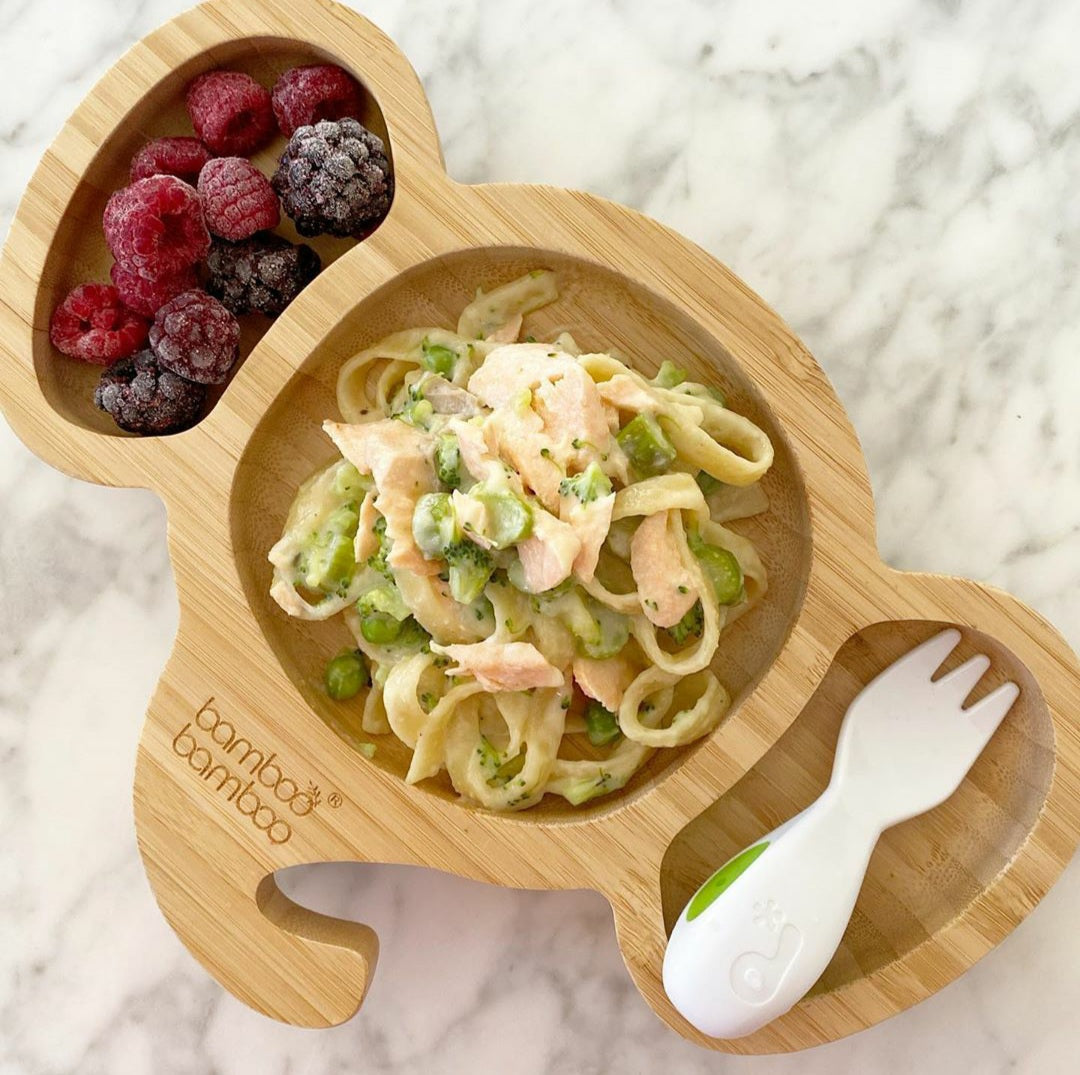 Mascarpone salmon pasta with peas and broccoli, served with berries in a bamboo plate.