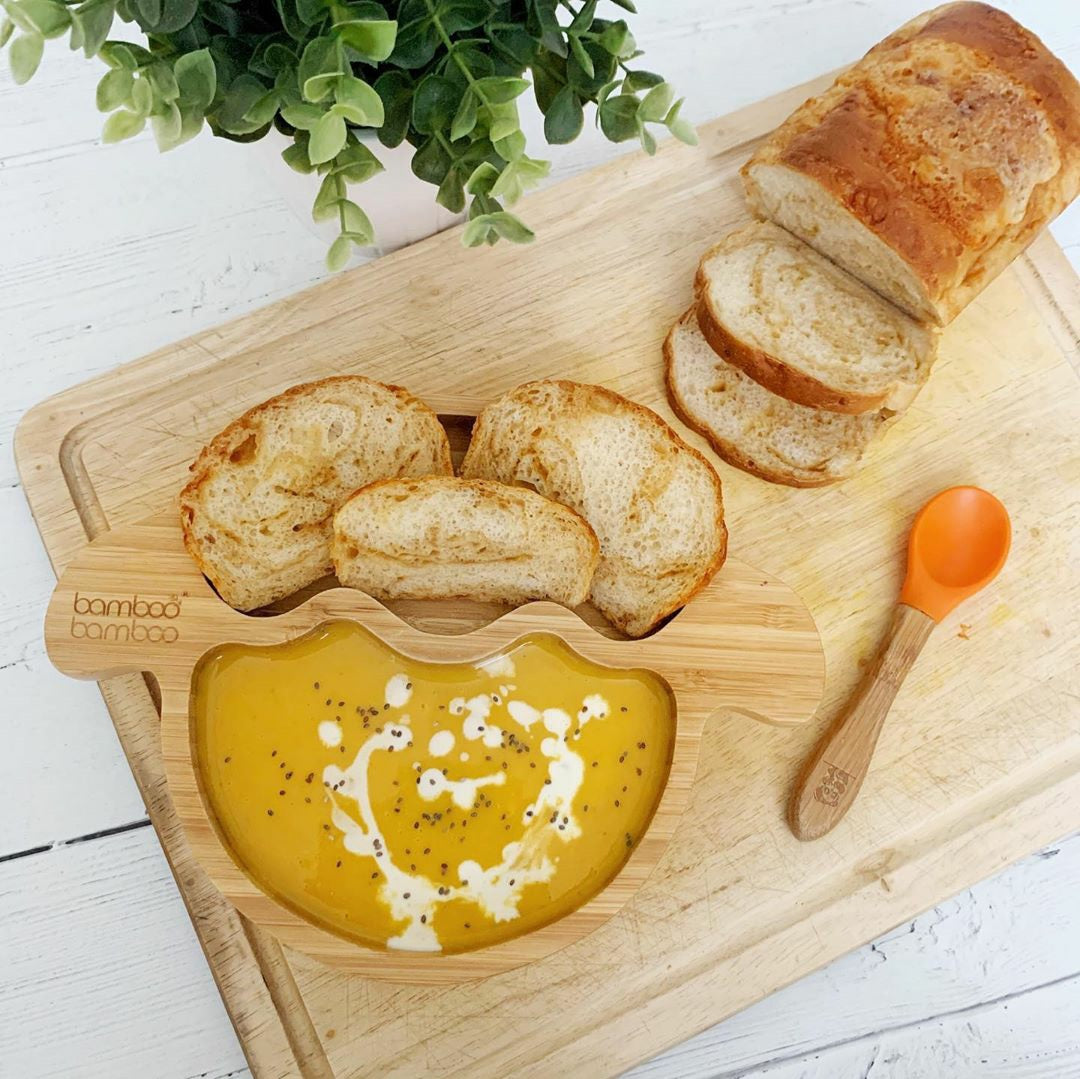 Creamy butternut squash soup with chia seeds and bread in a bamboo bowl.