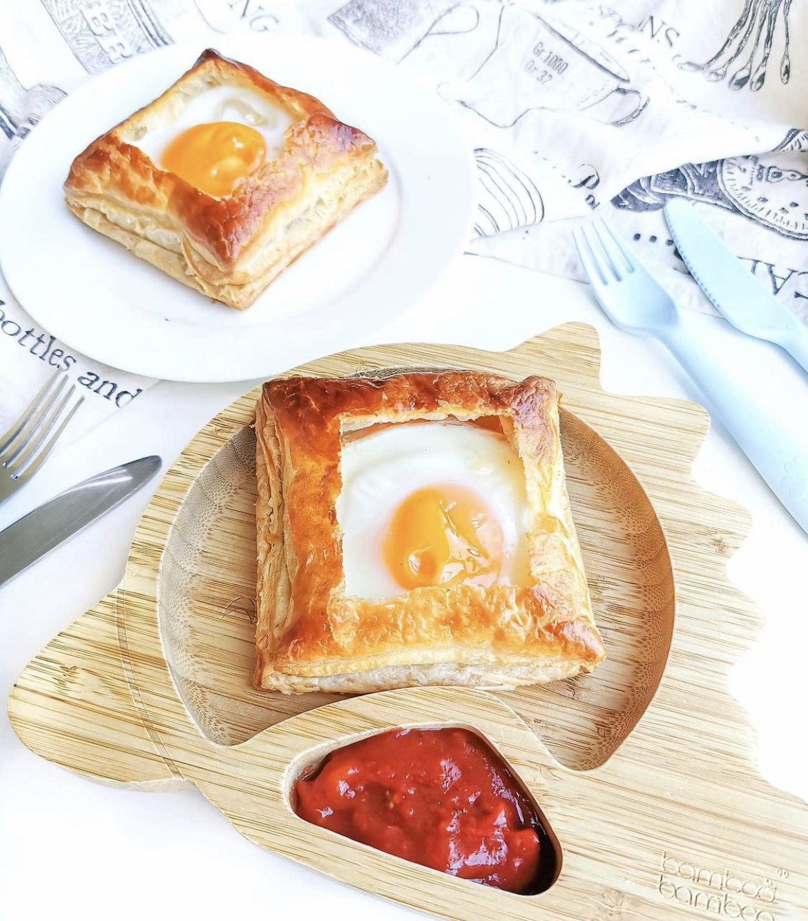 Golden puff pastry brunch cups with a fried egg, served on a bamboo plate with ketchup.