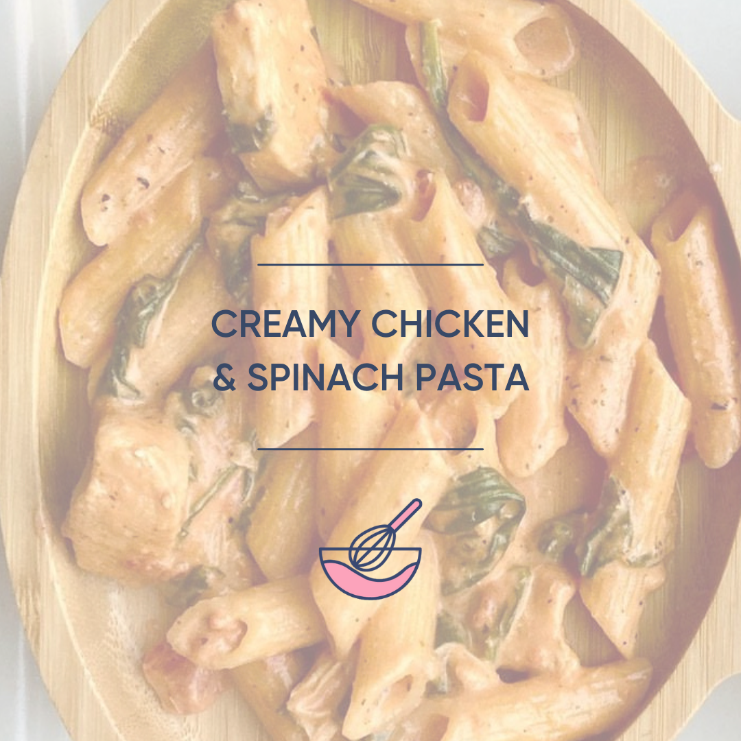 Creamy chicken and spinach penne pasta in a wooden bowl.