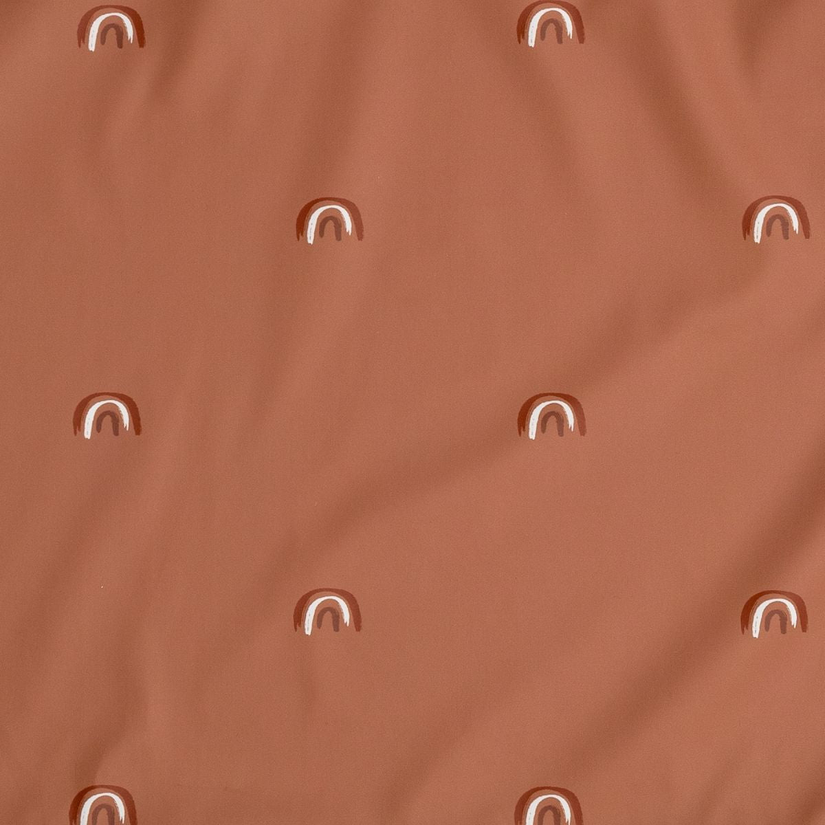 Brown fabric with a repeating pattern of small, hand-drawn white and brown rainbows. - Product image
