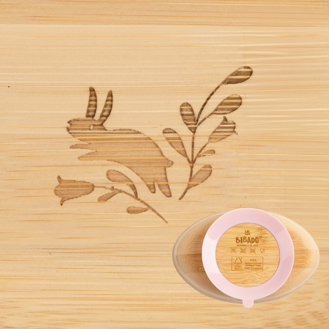 Close-up of a natural bamboo suction bowl with a pink base, featuring an engraved bunny and floral design. - Product image