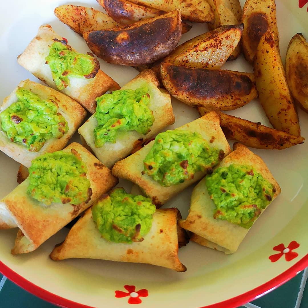 Golden baked "baby burritos" with vibrant green avocado mash, served alongside seasoned potato wedges.