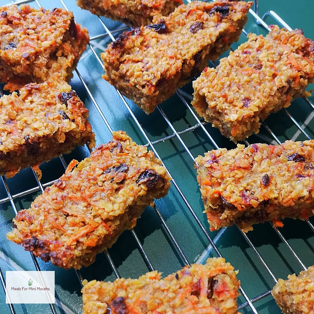 Golden-brown sweet and savoury flapjacks with oats, carrots, and raisins cooling on a wire rack.