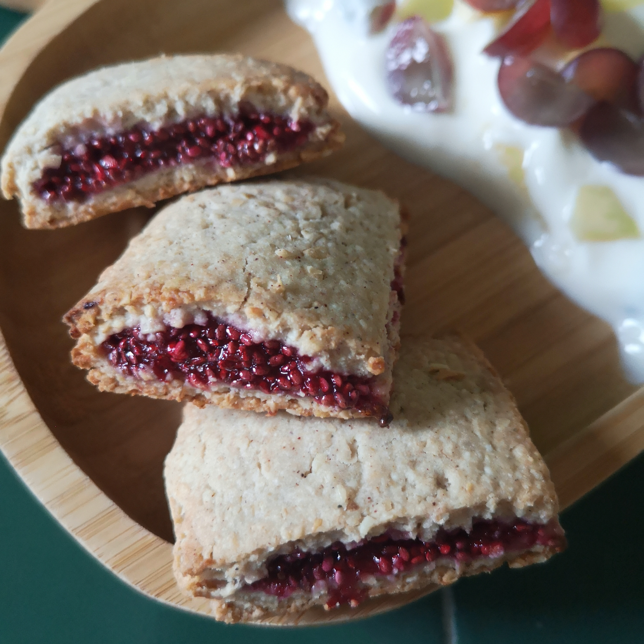Golden-brown fruity breakfast bites with vibrant raspberry filling, served with yoghurt and grapes.