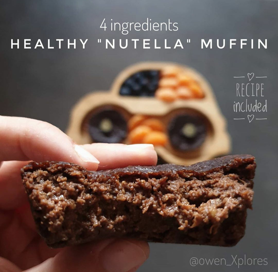Hand holding a rich, dark chocolate Nutella muffin, cut open to show its moist texture.