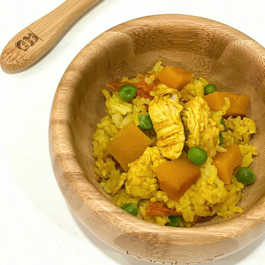 Chicken squash biryani with peas in a wooden bowl, next to a bamboo spoon.