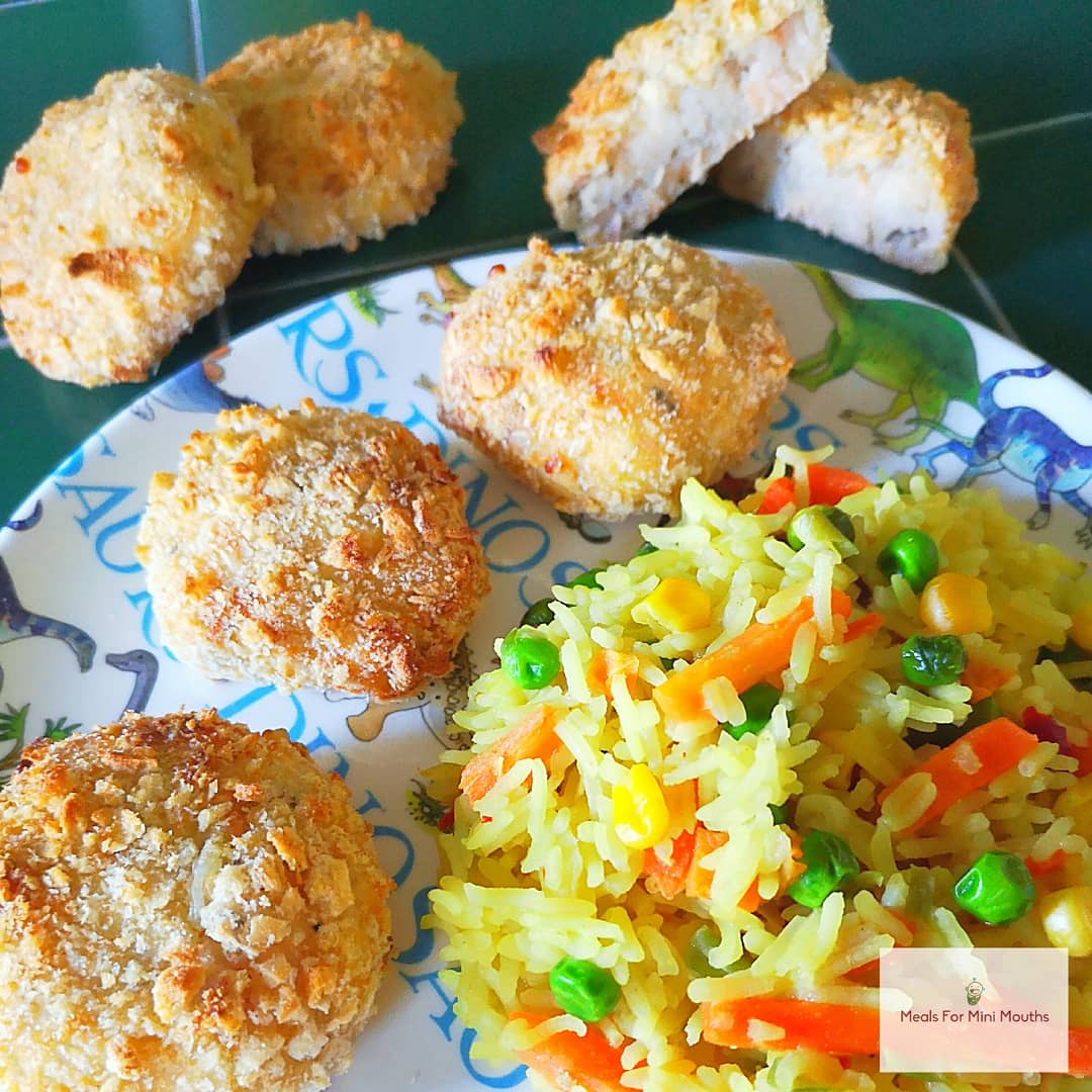 Golden-brown salmon and cauliflower fishcakes with colourful vegetable rice on a child's plate.