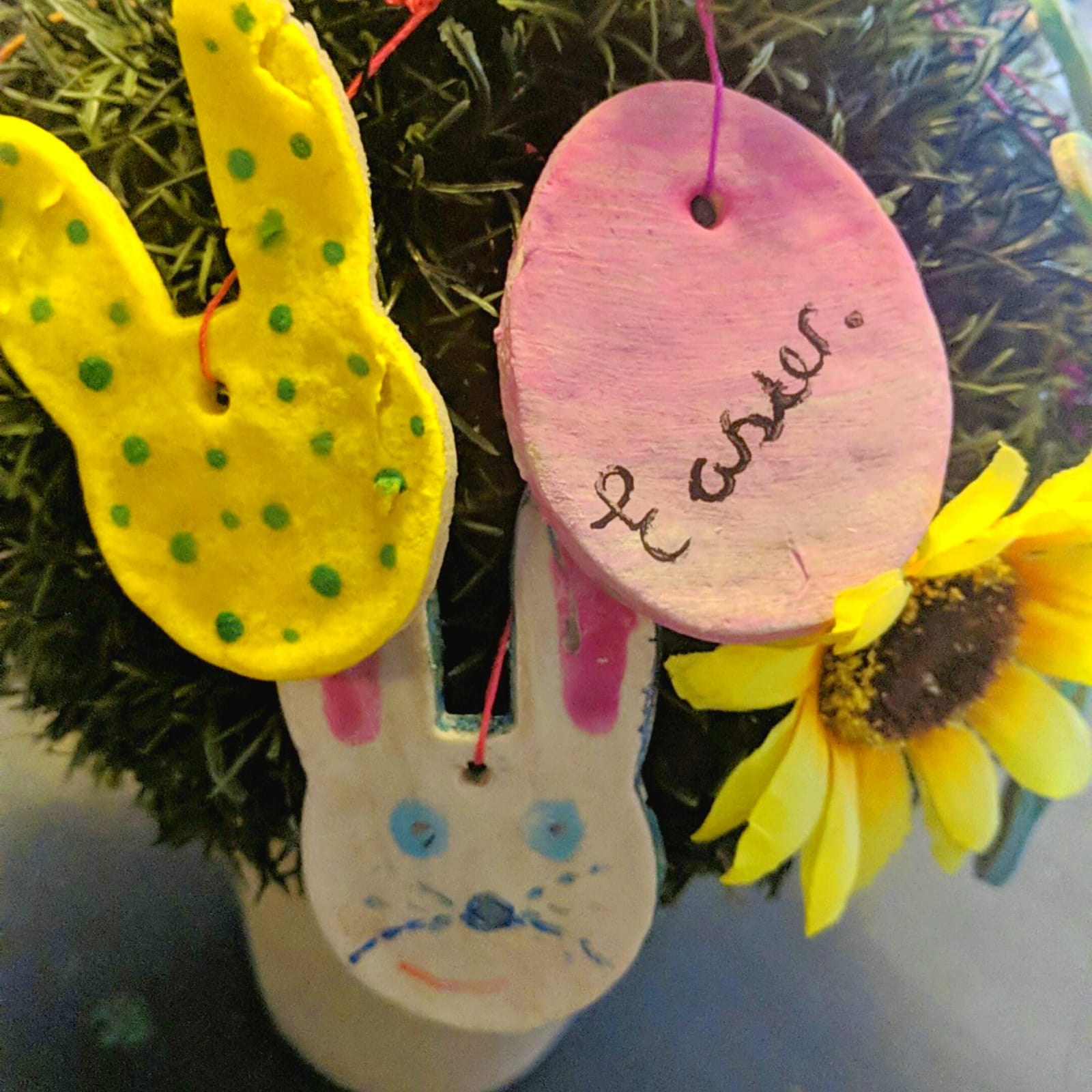 Handmade salt dough Easter decorations: yellow bunny, white bunny, and pink egg with "Easter" written on it.