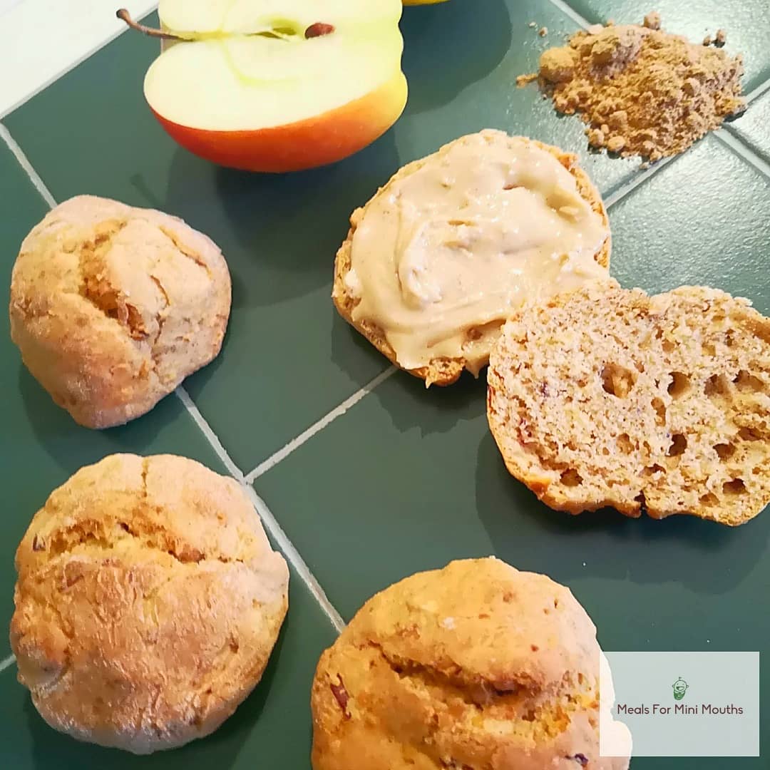 Golden ginger apple scones, one split with peanut butter, beside a halved apple and ginger powder.