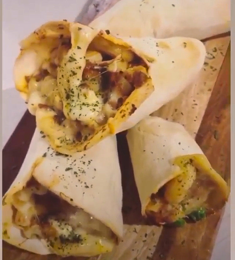 Three cheesy, golden-brown tacos filled with meat and herbs on a wooden board.