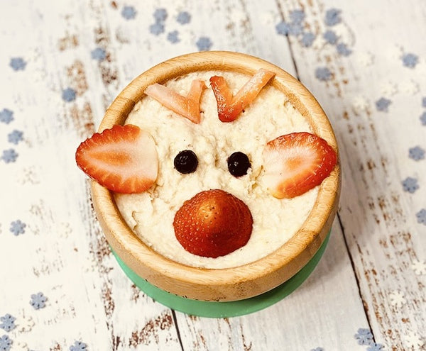 Rudolph porridge in a wooden bowl, decorated with strawberries and blueberries.