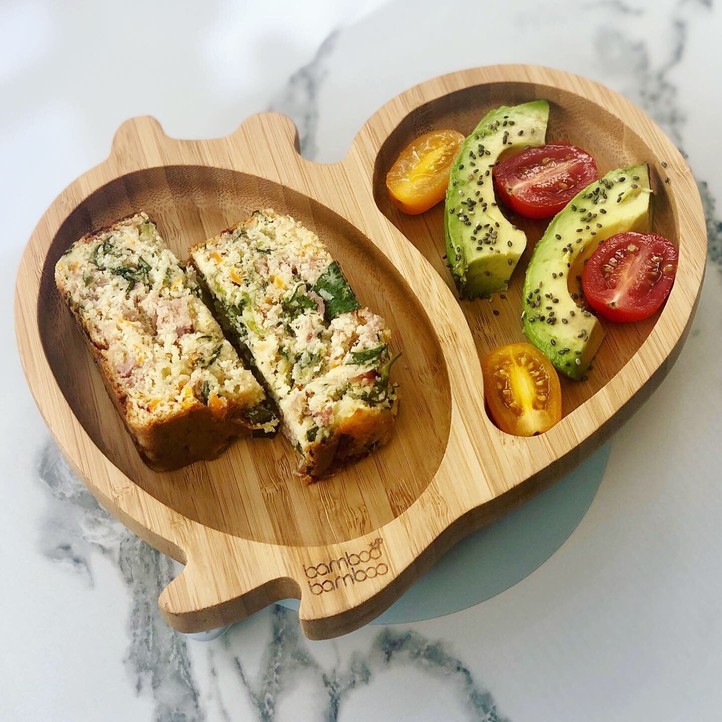 Savoury cornbread slices with avocado and cherry tomatoes on a bamboo plate.