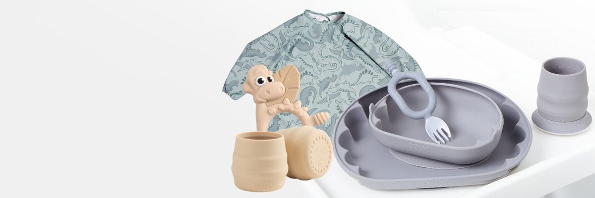 Spring bundles: baby bibs with giraffe and rainbow prints, silicone plates, bowls, and cups.