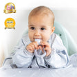 Happy baby in a grey star-patterned bib, holding and chewing a light grey silicone Dippit™ dual-ended spoon.