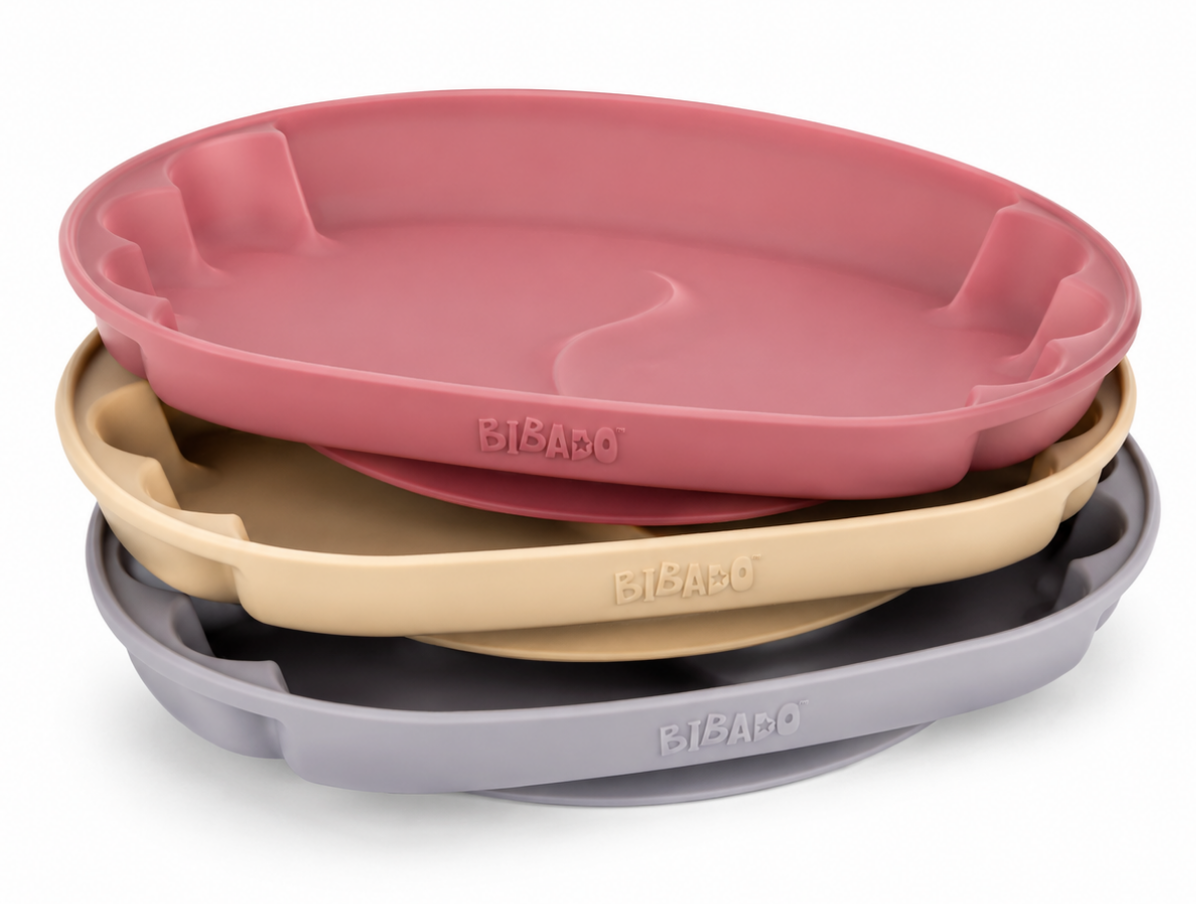 Three Bibado silicone baby plates in dusty pink, beige, and blue, stacked with the top pink plate slightly offset to show the scalloped rim and middle divider. - product info image