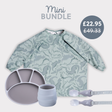 Sage green dinosaur print long-sleeve bib, grey silicone divided plate, light blue cup, and matching spoon/fork set.