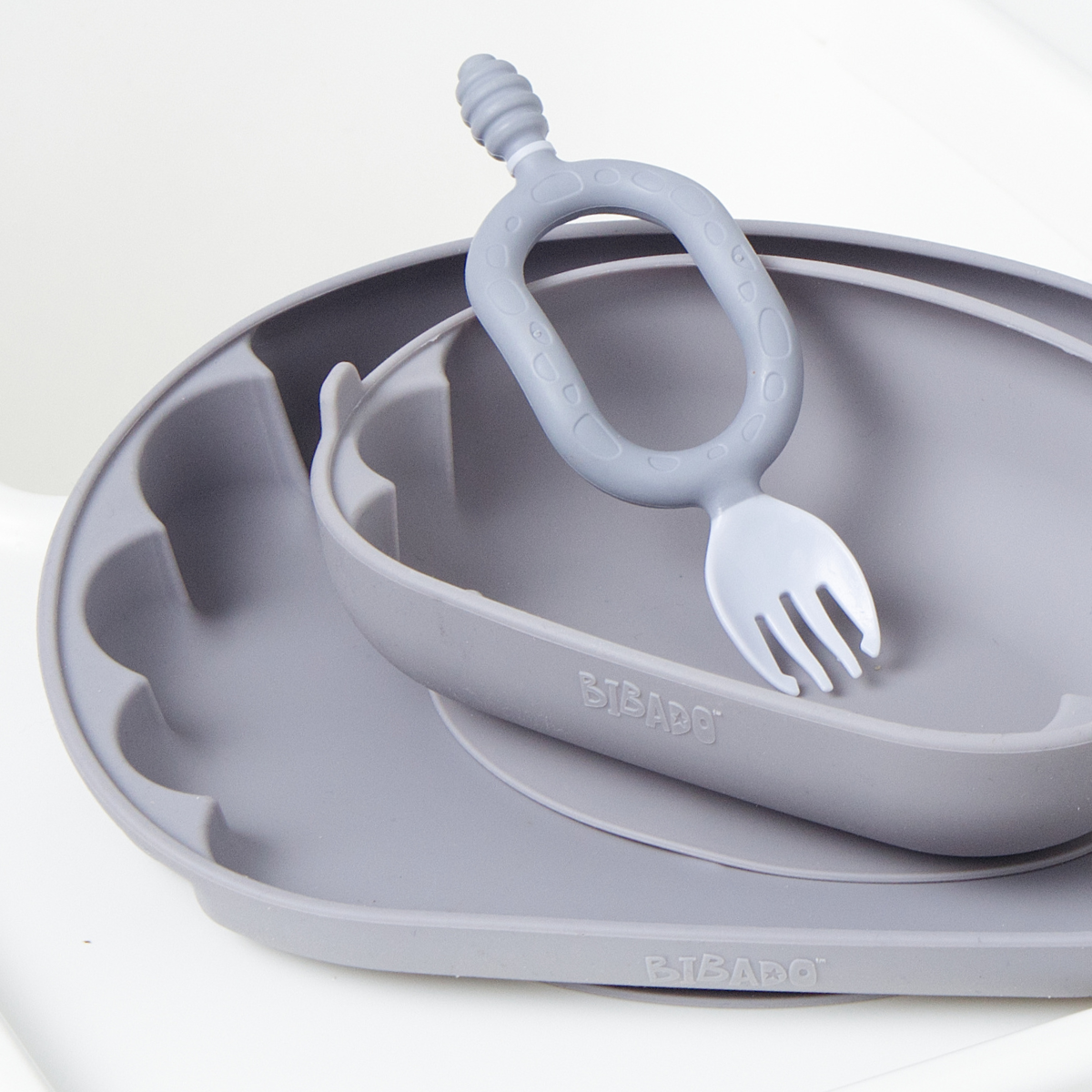 A blue-grey silicone baby feeding set, including a suction plate, a matching bowl, and a silicone Dippit shown on a white background. - Product image