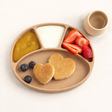 Children's plate with heart-shaped pancakes, fruit, and a small cup on a white background